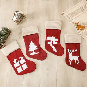 Set of 4 rustic red linen Christmas stockings with white festive patterns on wooden floor