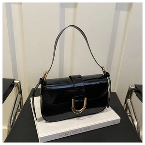 Close-up of black patent leather handbag featuring a golden horseshoe metal clasp detail