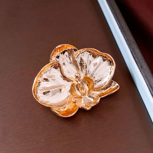 Macro shot of rose gold orchid brooch with fine bionic texture on dark display mat