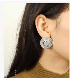 Close-up of silver hoop earrings with spiral texture shown worn on a model ear