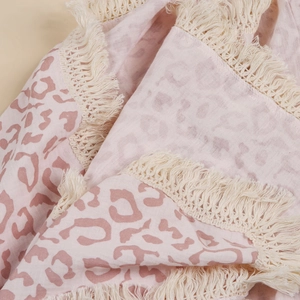 Close-up of pink leopard print cotton swaddle blanket with decorative cream fringe tassels