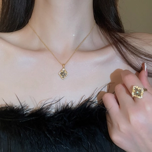 Close-up of gold-plated necklace and ring set with champagne square stones on model