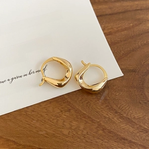Detailed close-up of 18K gold plated U-shaped earrings on a rustic wooden background