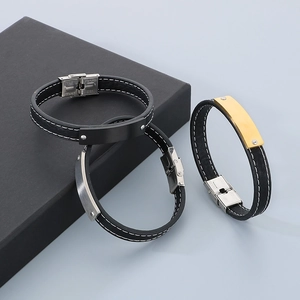 Detail of leather bracelets with black, silver, and gold stainless steel plates in a gift box
