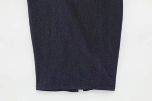 Détail macro de l'ourlet d'une robe en denim bleu foncé avec couture nette et fente centrale