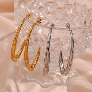 Polished gold and silver hoop earrings hanging on textured glass with silk backdrop