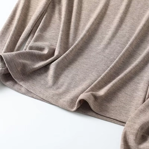 Detailaufnahme der hellbraunen Strickstruktur und des Saums am figurbetonten Oberteil