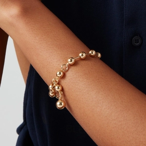 Vue macro d'un bracelet en perles de laiton doré brillant sur le poignet d'une femme