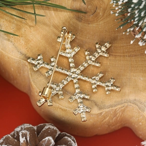 Back view of a gold snowflake brooch with safety pin detail and festive decor