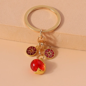 Detail of golden metal keychain with red pendants featuring auspicious Chinese symbols