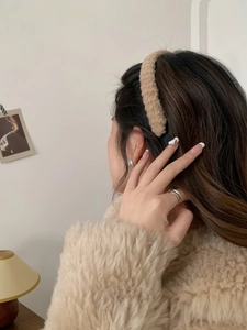 Close-up of soft brown plush headband worn by a model in a cozy indoor setting