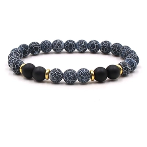 Detail of beaded bracelet with blue turquoise, matte onyx, and gold spacers on white background
