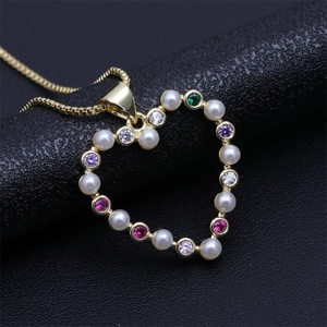 Close-up of golden heart pendant with white pearls and multi-colored gemstones on black