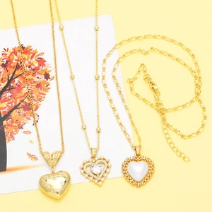 Three different gold-plated heart pendant necklaces with pearl and zircon details on a card
