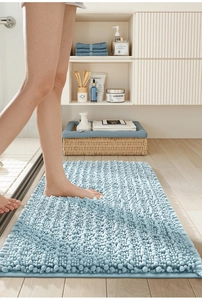 Absorbent light blue chenille bath mat shown with bare feet stepping on soft texture