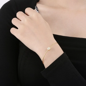 Detail of gold-plated stainless steel wire bracelet with a round zircon stone on model wrist
