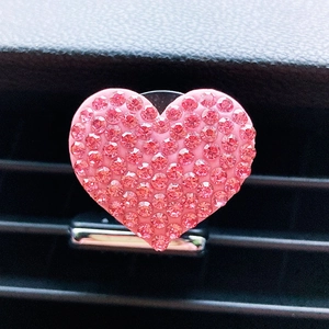 Close-up of pink heart-shaped car air vent clip with sparkling rhinestones decoration
