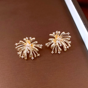 Macro shot of vintage gold firework stud earrings featuring white cubic zirconia stones