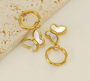 Détail de boucles d'oreilles créoles papillon dorées avec incrustation de nacre
