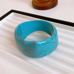 Close-up of wide turquoise blue marble resin open bangle with polished gold plating