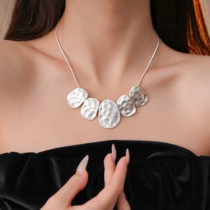 Detail of silver hammered irregular oval pendants on a sleek snake chain necklace