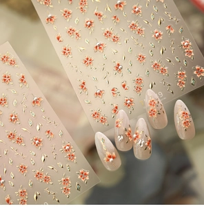 Macro view of 3D retro floral nail stickers with orange petals and golden embossed details