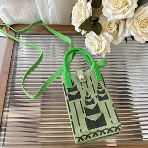 Detail of green and black knitted crossbody phone bag with geometric ethnic pattern