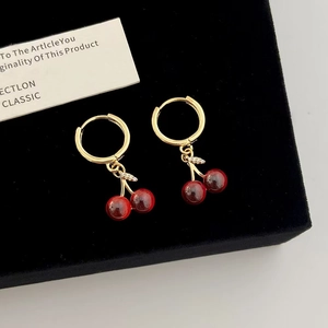 Orecchini a ciliegia con perline rosse e zirconi micro-incastonati su sfondo di velluto nero