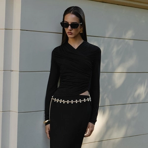 Close-up of elegant black V-neck ruched top styled with a pearl chain belt and sunglasses