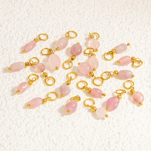 Detailed view of pink natural stone pendants with gold metal loops for DIY jewelry making