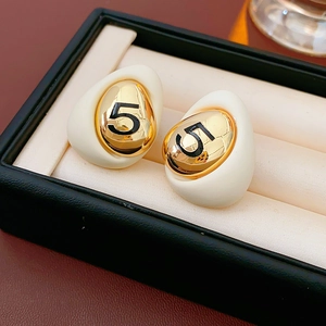 Detailed macro of vintage style gold-plated oval earrings with black number five