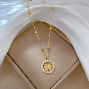 Close-up of golden butterfly ring pendant with crystals and beaded chain necklace