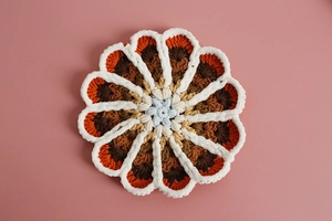 Macro view of floral crochet coaster showing gradient blue and orange yarn texture