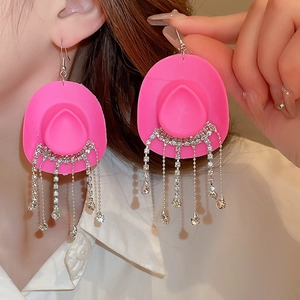 Detail showing pink cowboy hat earrings with sparkling rhinestone fringe on a model