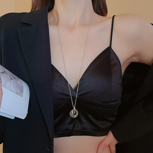 Close-up of interlocking silver ring pendant necklace on a model wearing black silk
