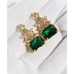 Retro emerald green crystal earrings in gold setting held with white gloves