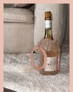 Close-up of luxury pink rhinestone mesh wine bag on champagne bottle in home setting