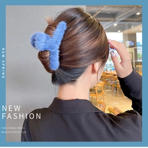 Blue faux fur claw clip shown on a woman hair with a stylish indoor aesthetic