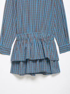 Détail de la robe courte à carreaux avec taille élastique et jupe à volants superposés