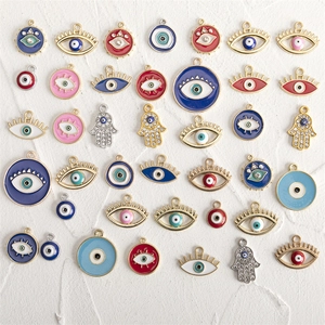 Flat lay view of colorful enamel and rhinestone Evil Eye and Hamsa Hand jewelry charms