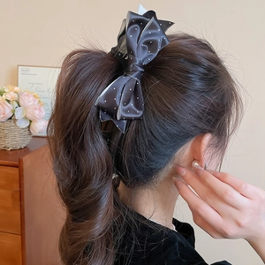 Detailed back view of a black polka dot satin bow hair claw clip styled on a ponytail