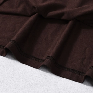 Close-up of double-stitched hem on a dark brown knit dress with wave lace details
