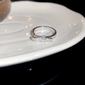 Detailed close-up of a silver bow ring with shimmering cubic zirconia on a white tray