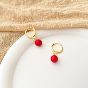 Detail of gold small hoop earrings with red pearl charms and S925 stamp engraving