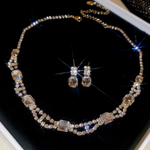 Macro view of crystal square pendant necklace and earrings set on black velvet