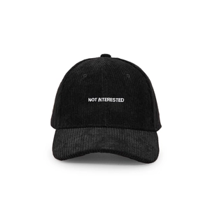 Detail of the NOT INTERESTED white embroidery on the black corduroy baseball cap
