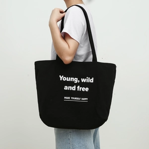 Detail of black canvas tote bag with Young, Wild and Free white printed text lettering