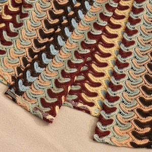 Macro detail of multi-colored crochet wavy pattern texture on loose long sleeve shirt