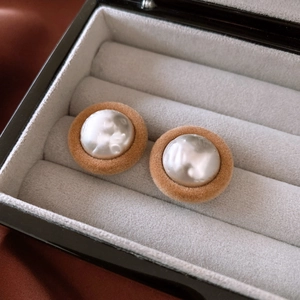 Close-up of vintage camel plush button earrings with baroque faux pearls in a box