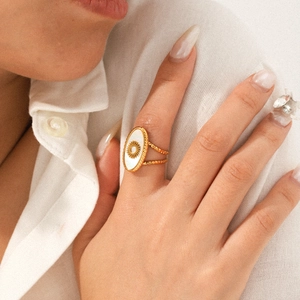 Close-up of gold stainless steel ring with white shell inlay and sun relief on a model